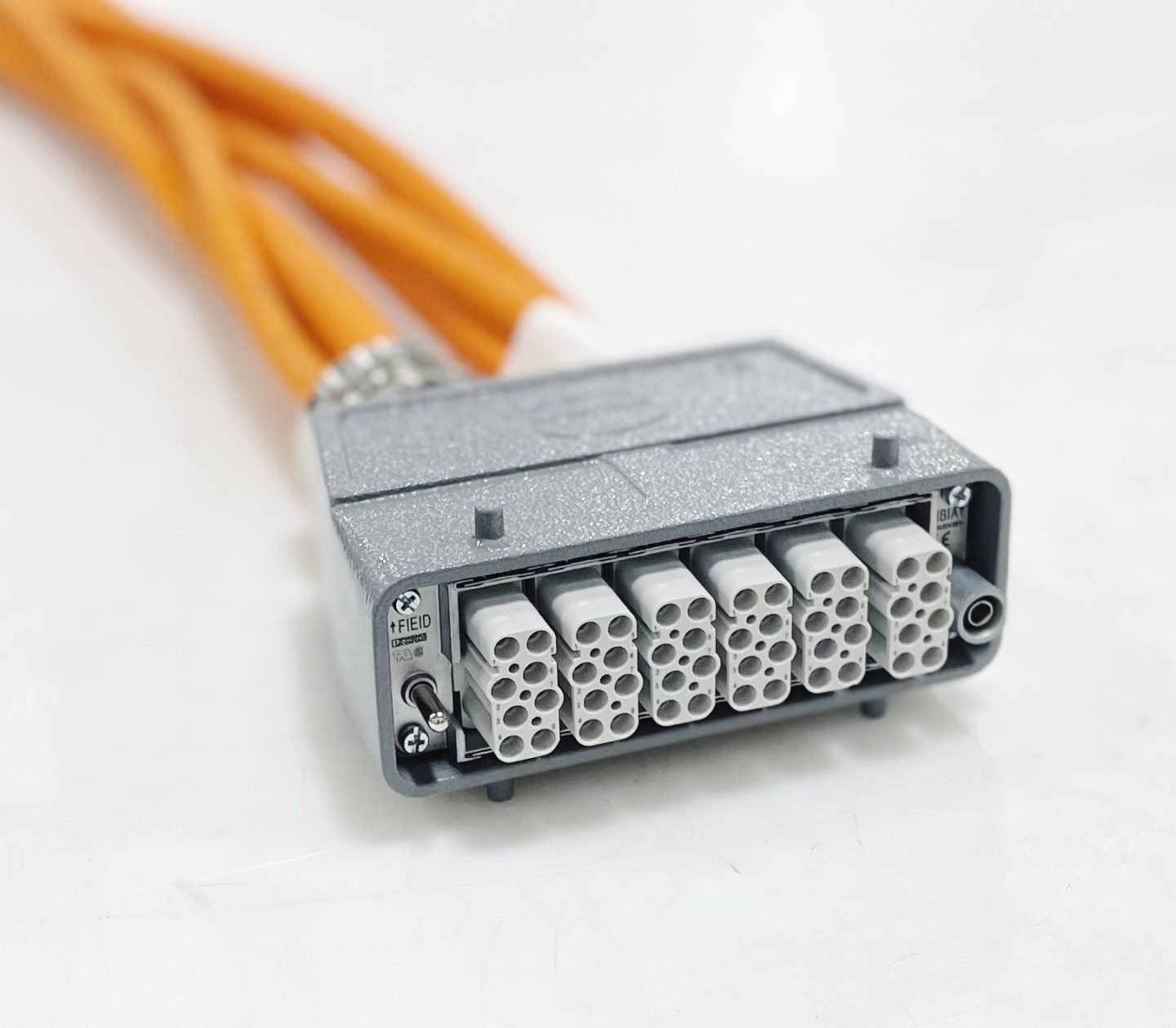 An orange multi-core electrical cable with a rectangular connector head featuring multiple round pins on a light gray surface.