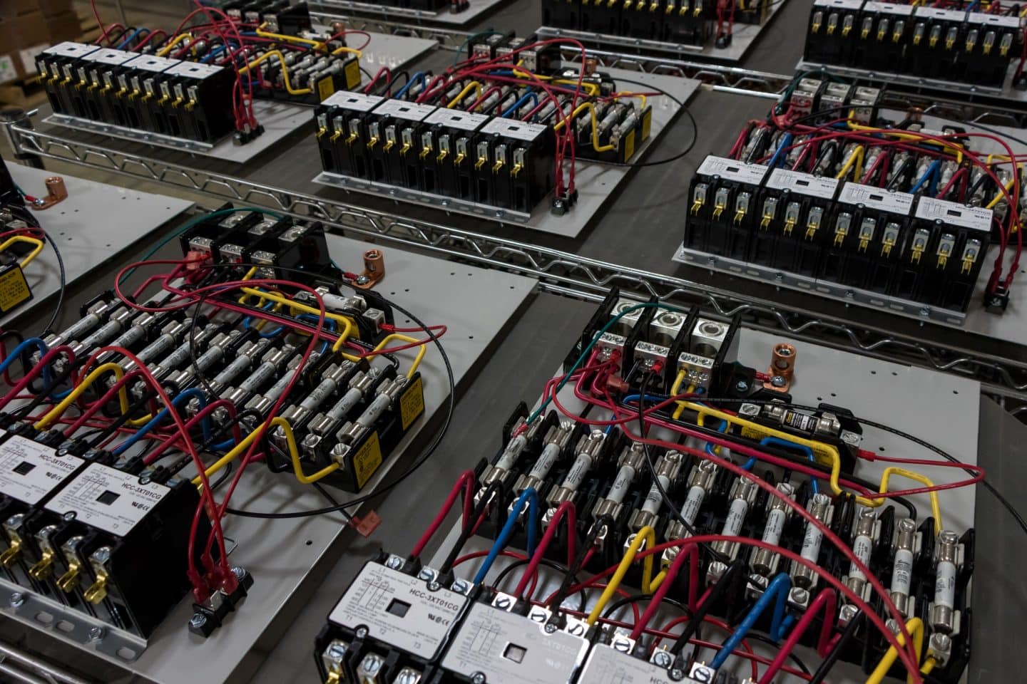 Close-up of multiple electronic circuit boards with various wires, connectors, and components arranged neatly on a metal rack.