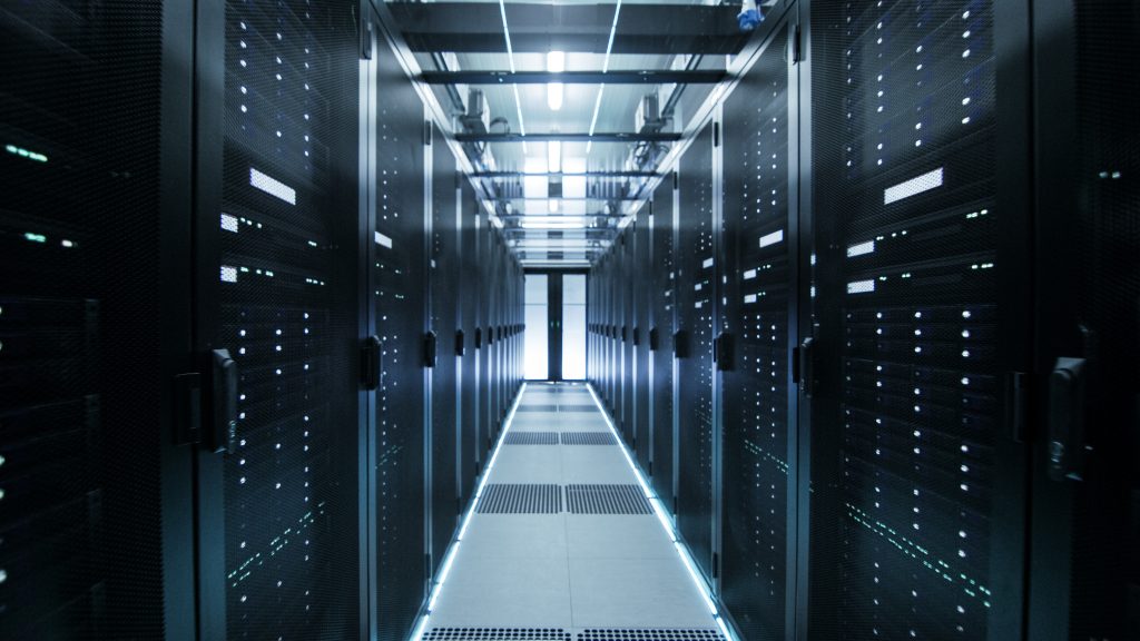 A dimly lit data center aisle with server racks on both sides, blue LED lights highlighting the equipment, and a reflective floor.