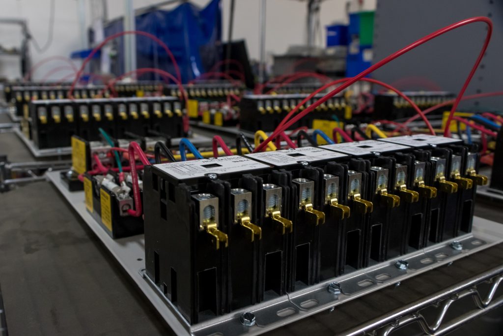 Close-up of electrical circuit breakers with red and blue wiring in an industrial setting.